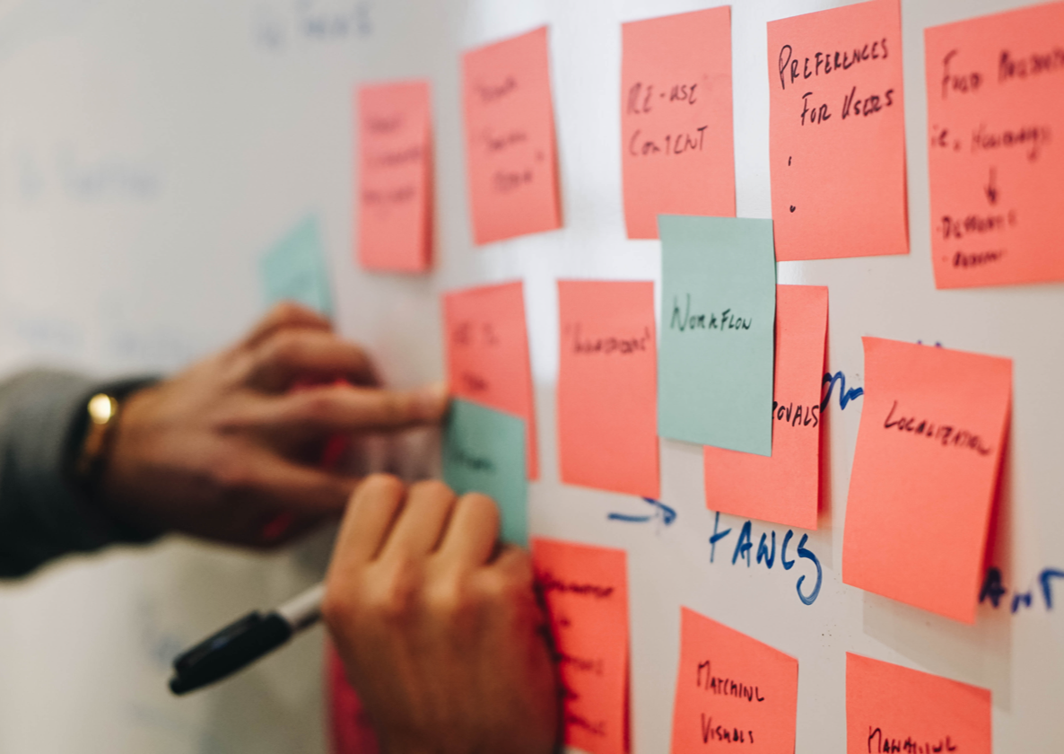 A person writing on sticky notes on a whiteboard.