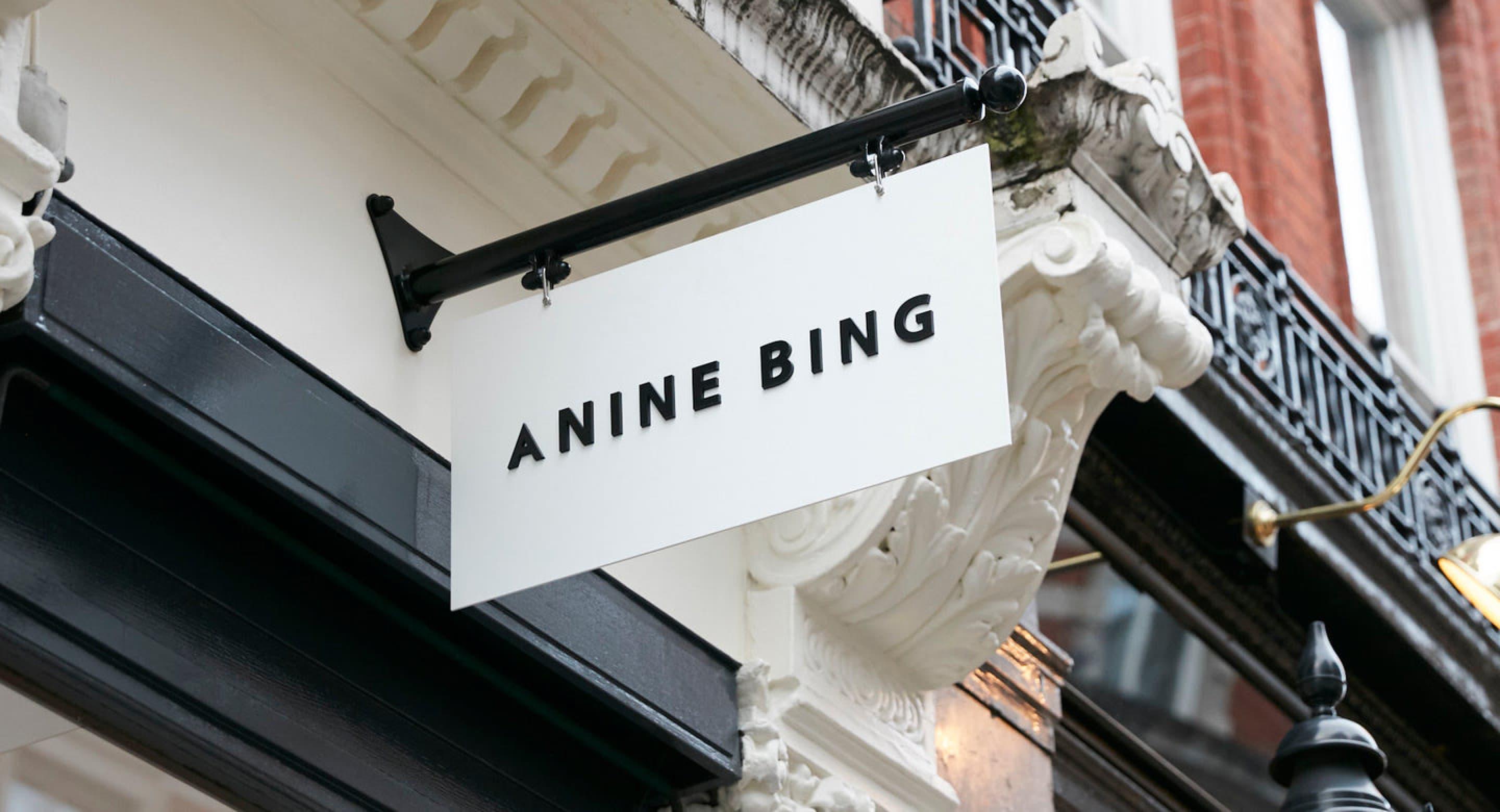Un letrero de tienda ANINE BING colgando fuera del escaparate en una calle.