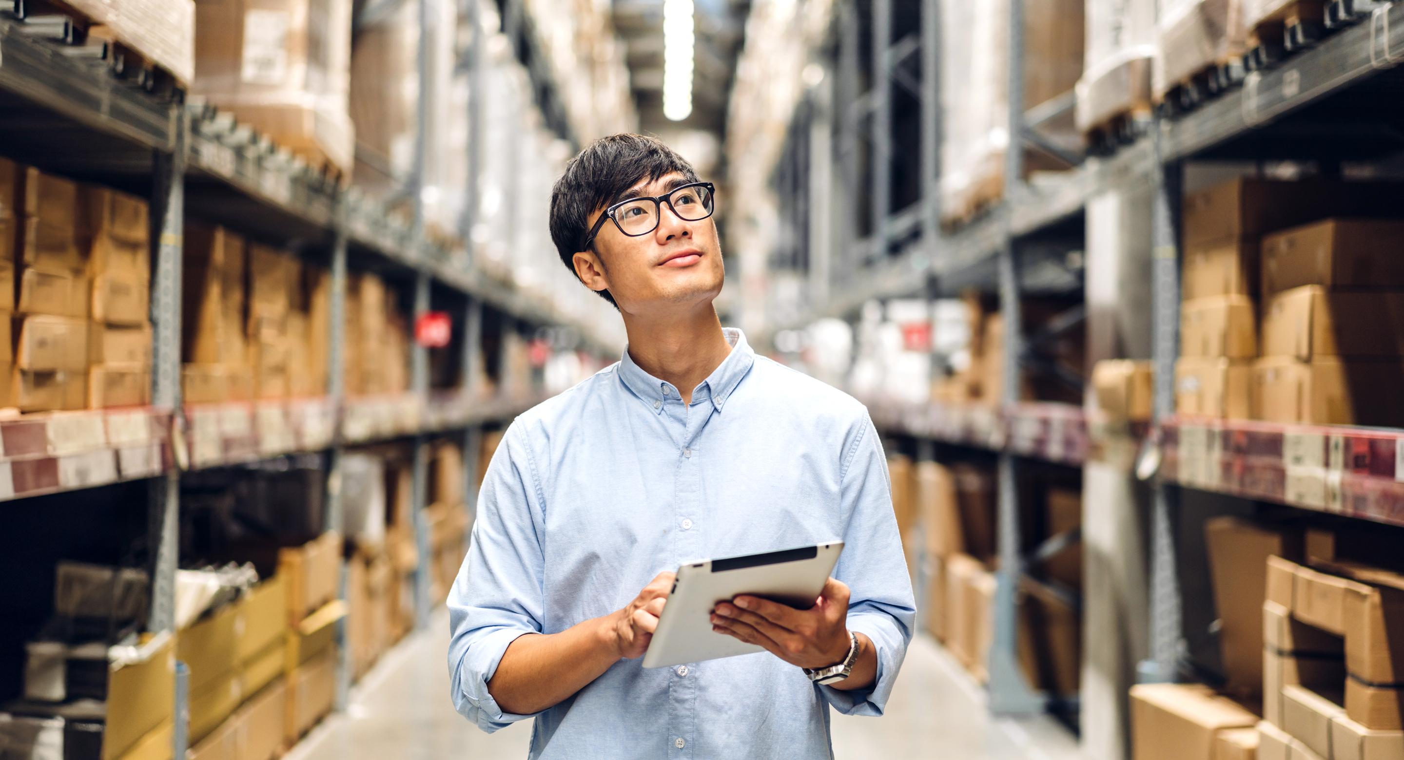 A photo of a man in a warehouse with a tablet in hand.