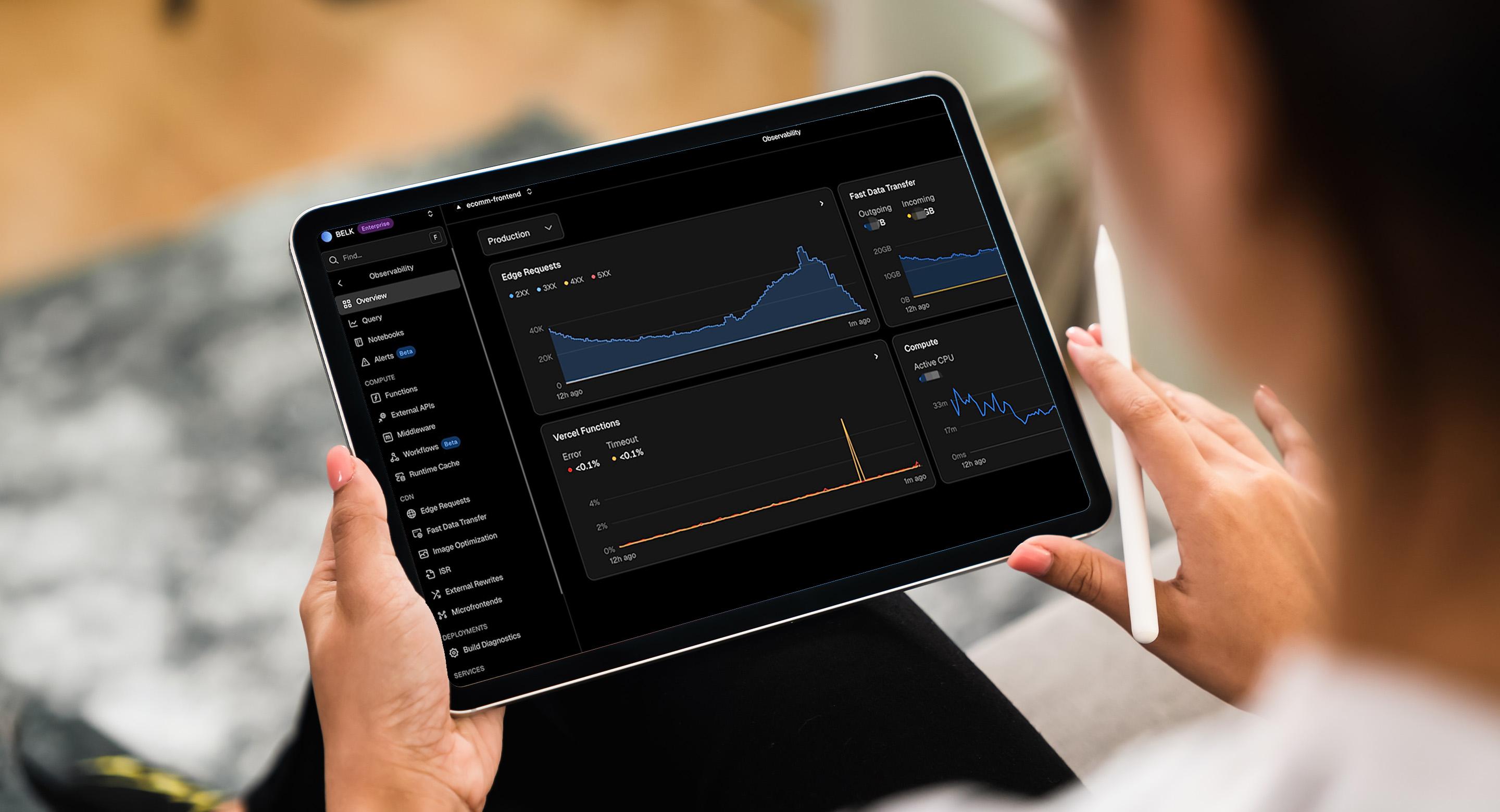 Person holding a tablet displaying a dark-themed observability dashboard with performance graphs for edge requests, fast data transfer, and serverless functions.