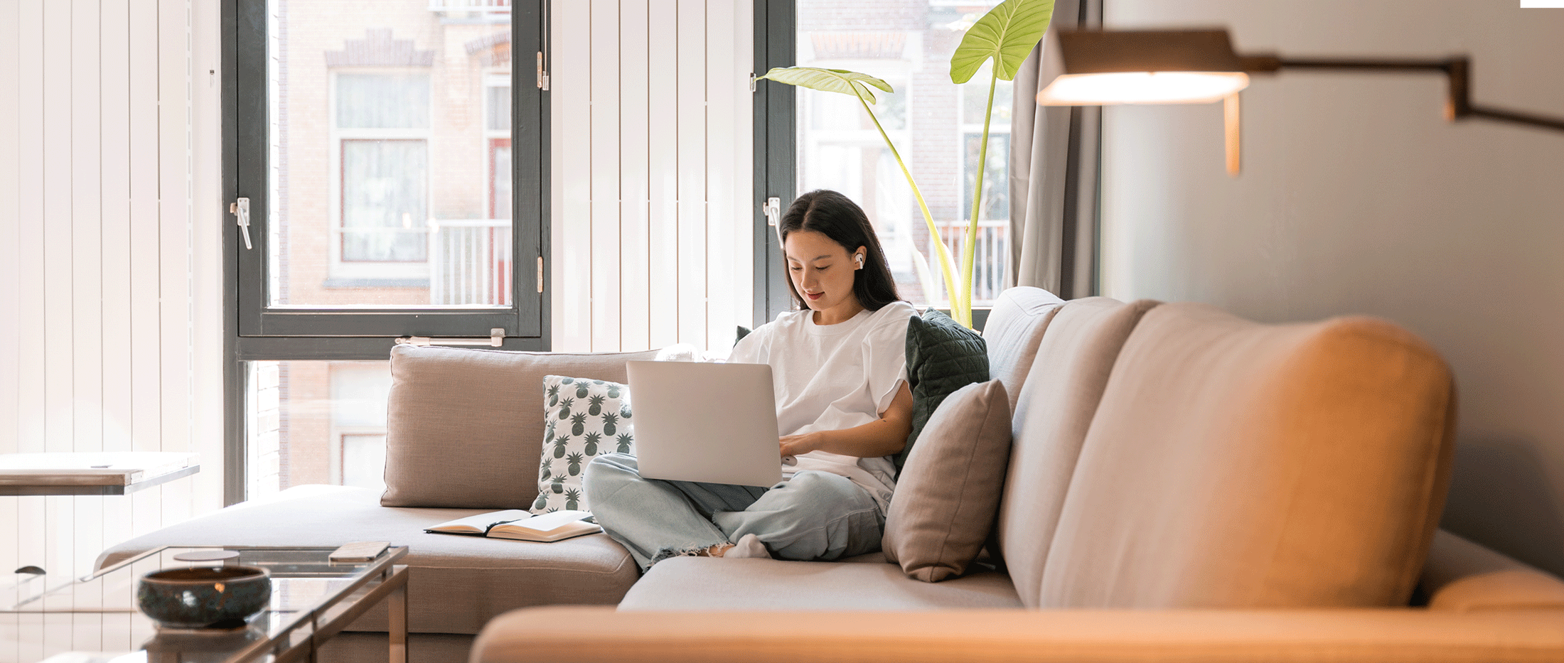 Lady on her couch working with her laptop.