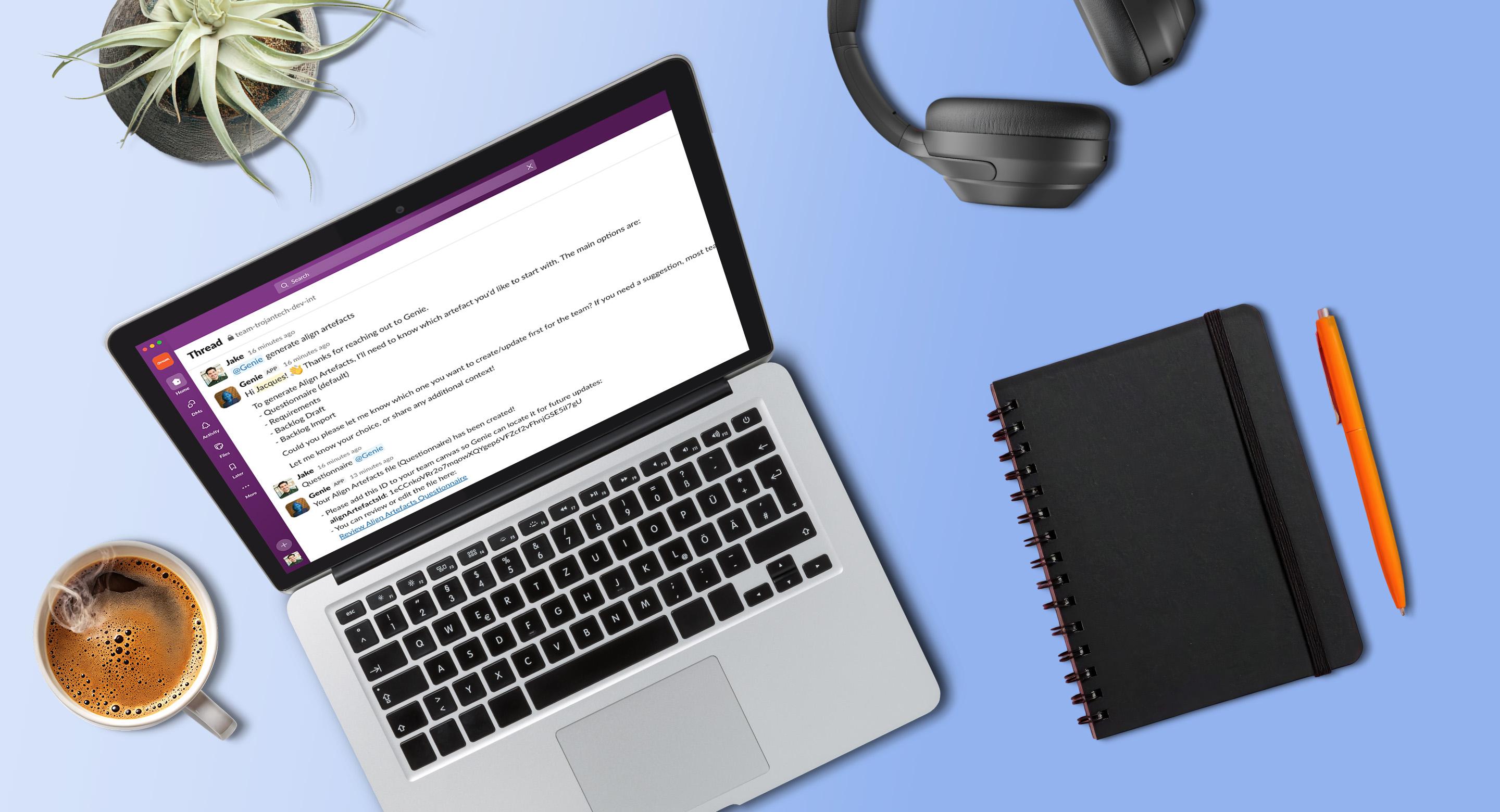 Laptop displaying a Slack thread on a desk with a coffee cup, notebook, pen, headphones, and a small plant arranged around it.