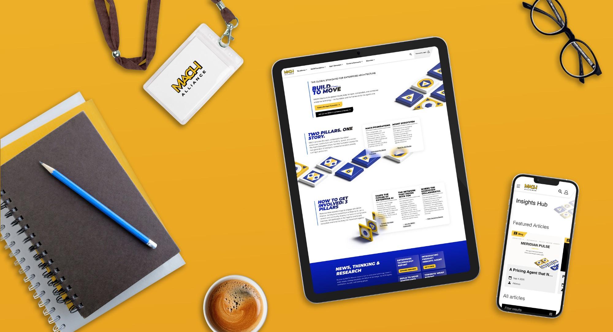 Vista cenital de una tableta y un teléfono mostrando el sitio web de la MACH Alliance, rodeados de un gafete con cordón de la MACH Alliance, cuadernos, un lápiz, gafas y un café sobre un escritorio amarillo.