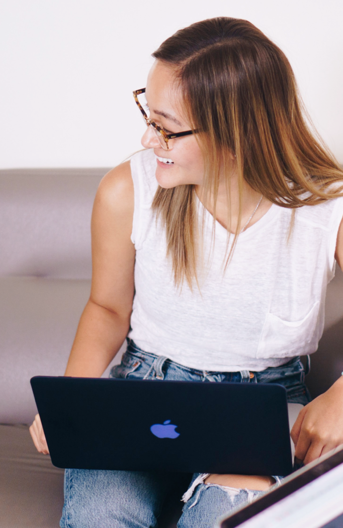 Orium employee with a Macbook on their lap, smiling at something to the side of them.