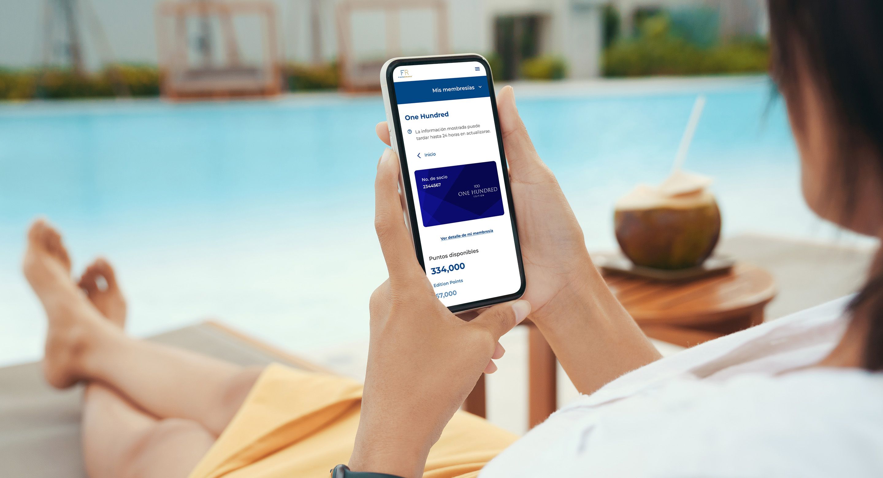 A woman sits poolside with her smartphone in hand reviewing her Gropo Posadas loyalty account