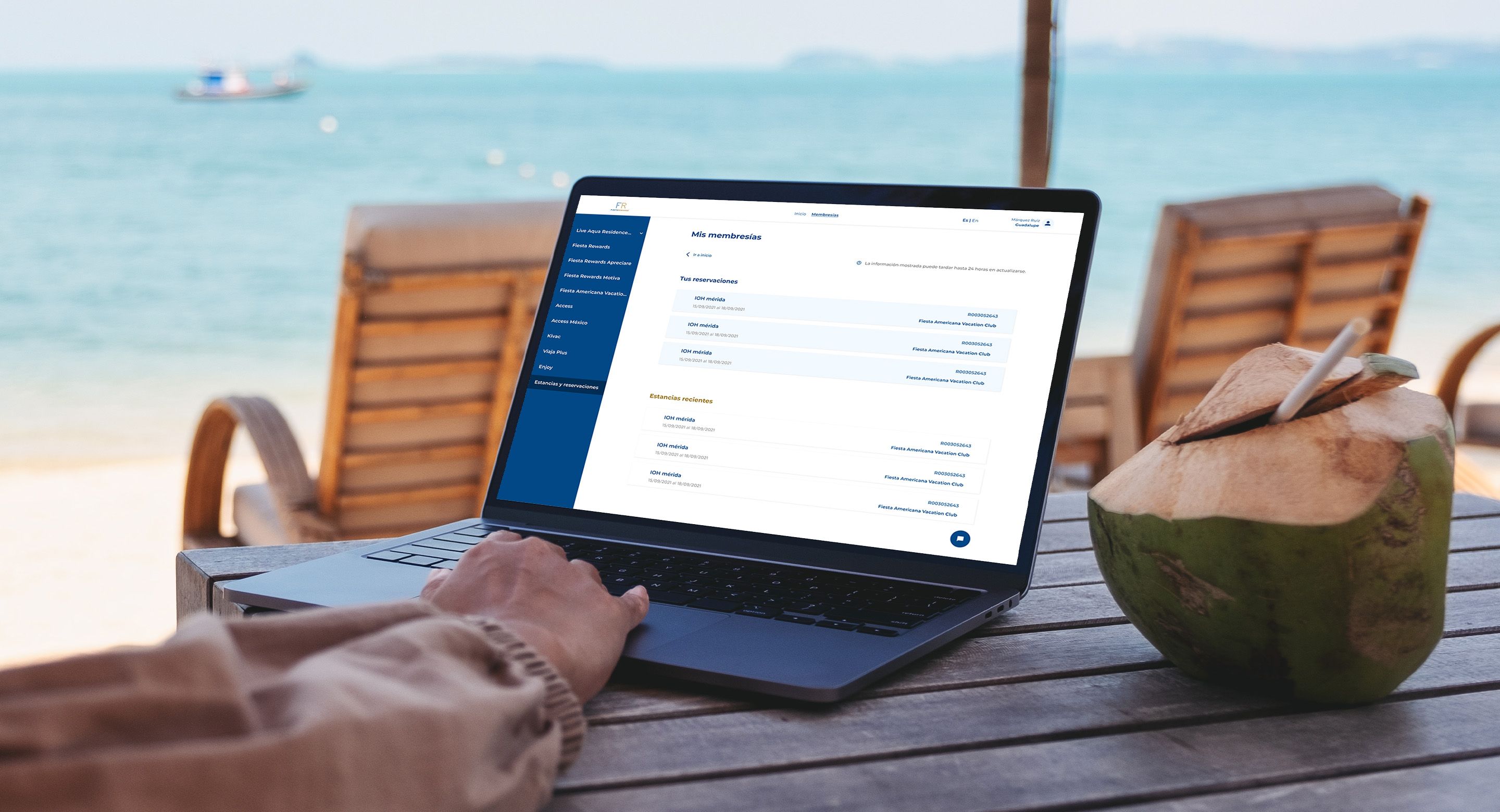 A person uses their laptop at a beachfront table to explore their membership accounts