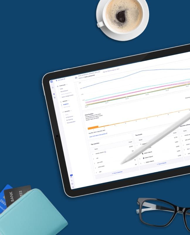 Flatlay of an iPad with analytics , a cup of coffee, a wallet with some credit cards peeking out, and a pair of glasses.