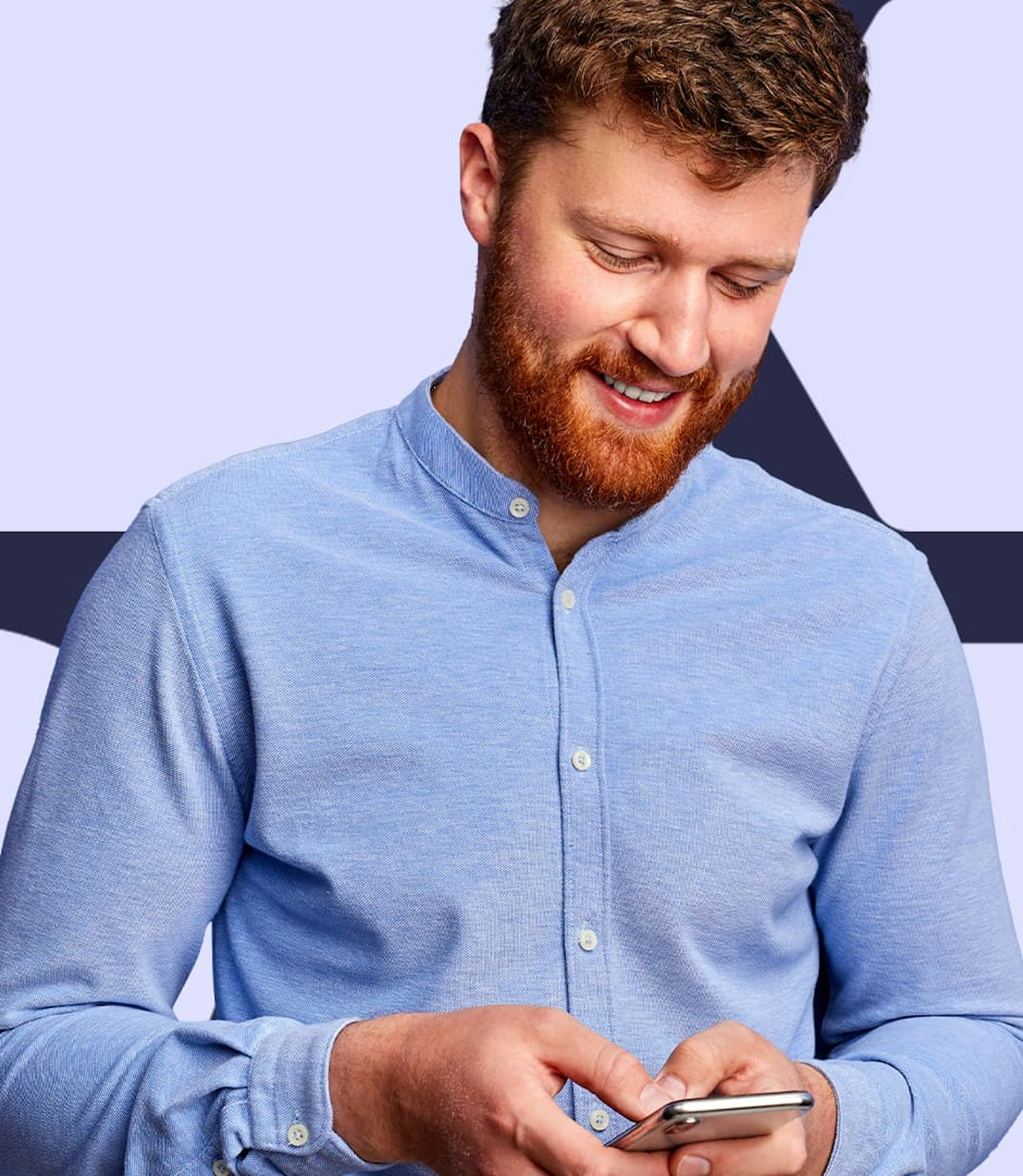 A man wearing a blue shirt looking down at his cellphone.