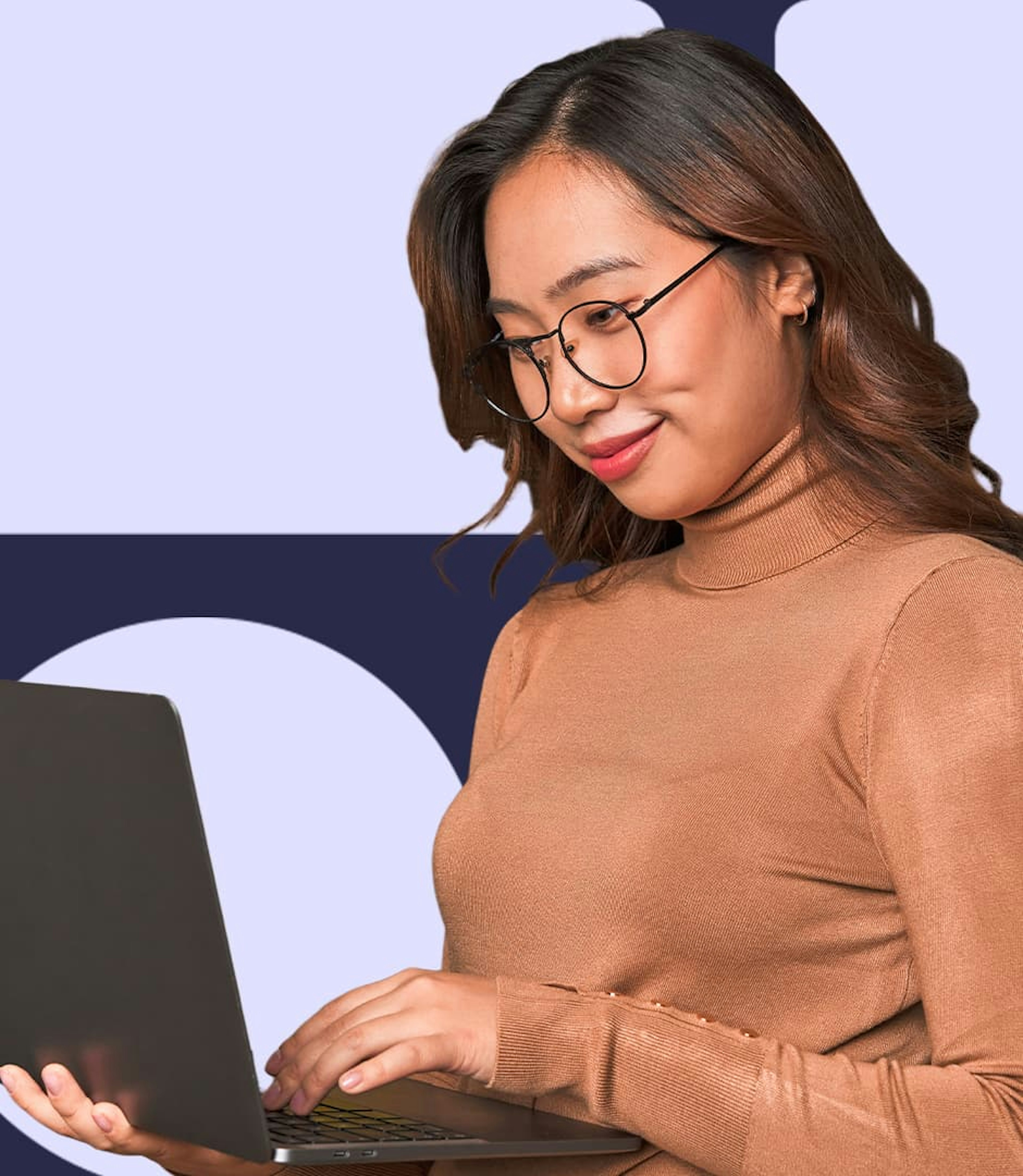 A woman wearing a tan turtleneck and glasses is holding a laptop and working.