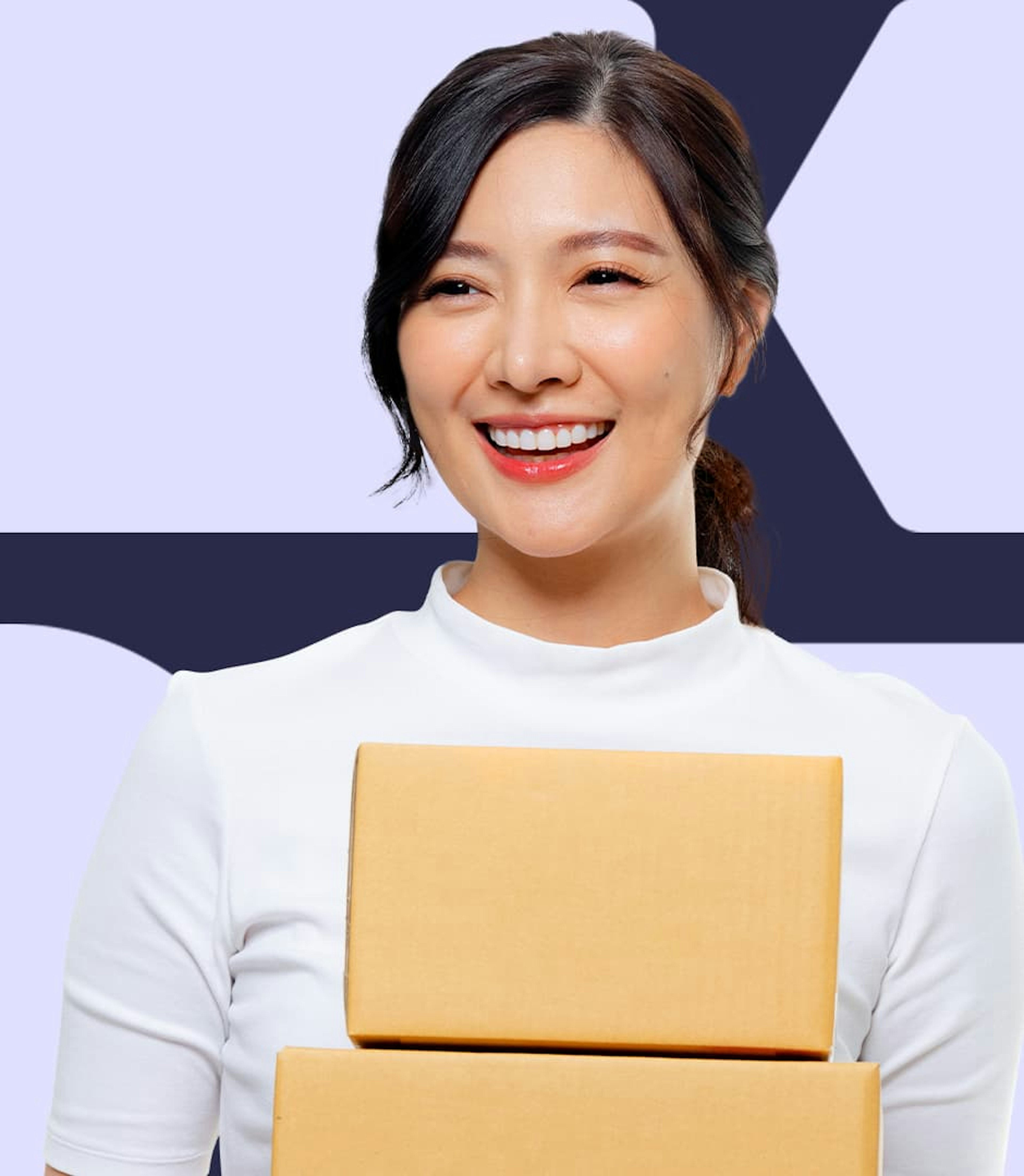 A woman wearing a white shirt is smiling and carrying two stacked cardboard boxes in her hands.