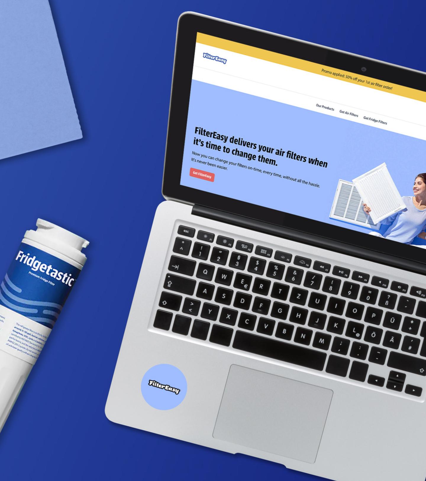 A laptop showing the FilterEasy website on a blue background with a Fridgetastic fridge filter product.