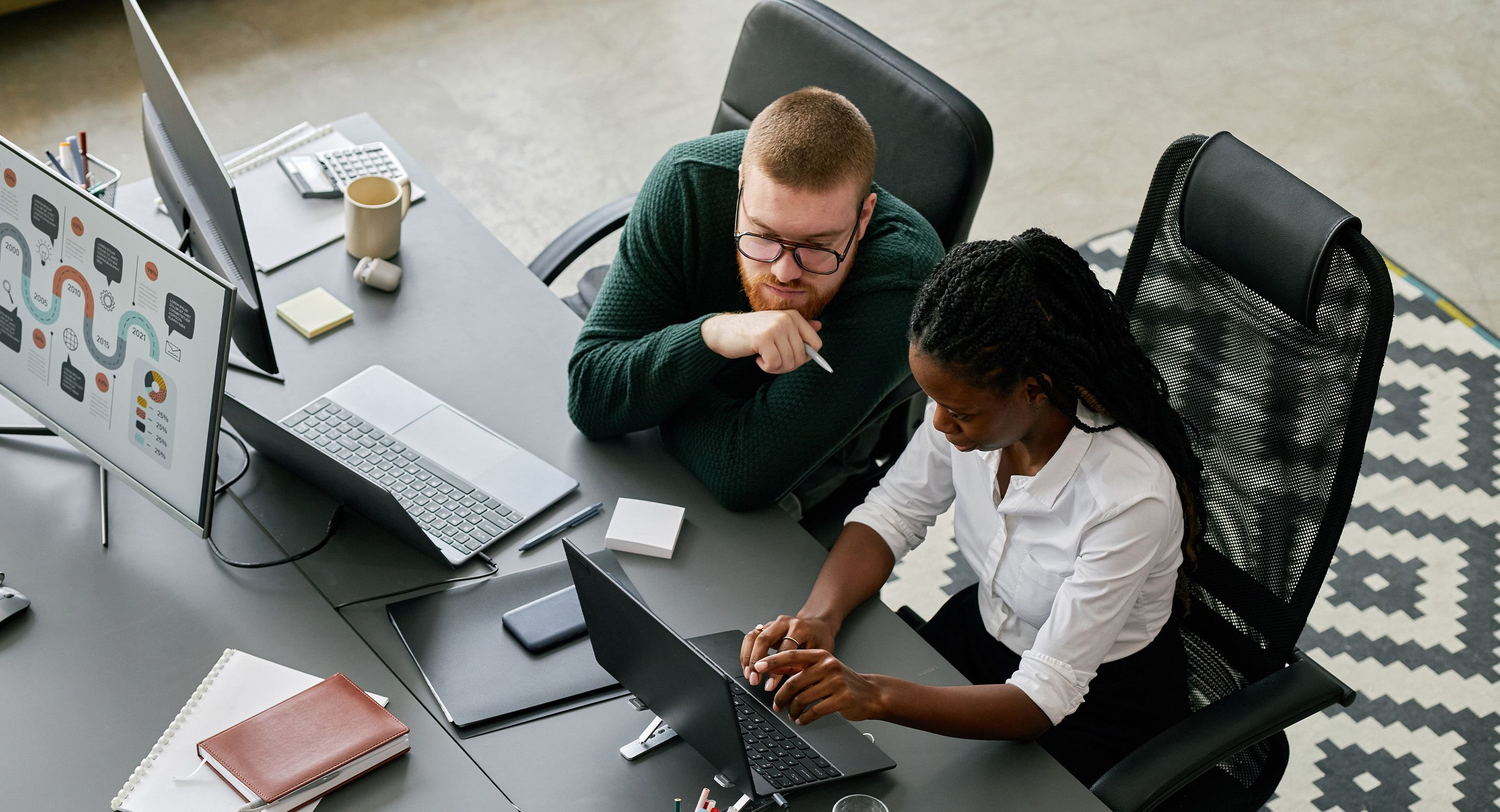 Two colleagues reviewing data and collaborating at a shared desk