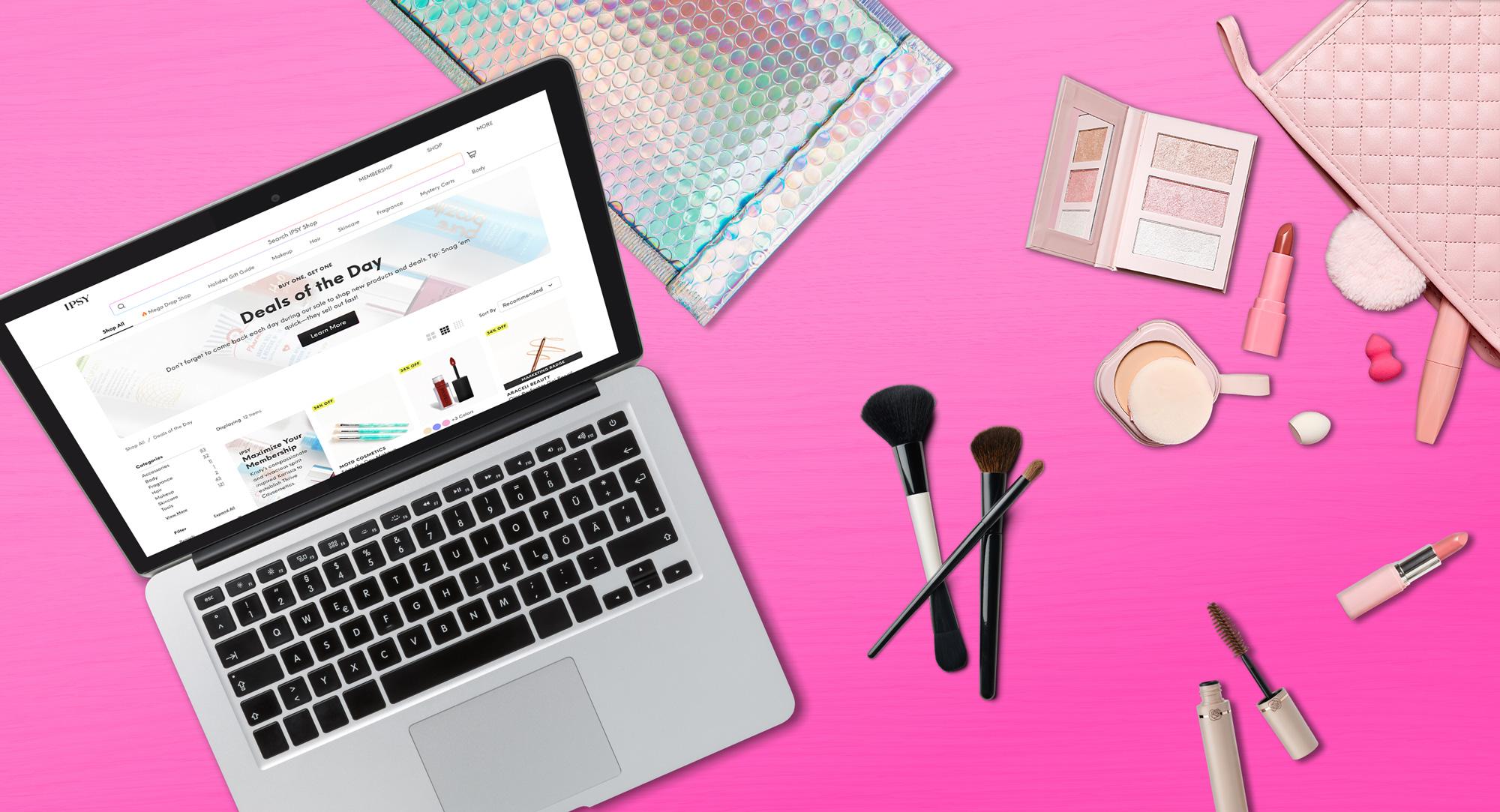 A laptop showing a product page on the IPSY website with select makeup items including a lipstick, brush, and a mascara beside the laptop.
