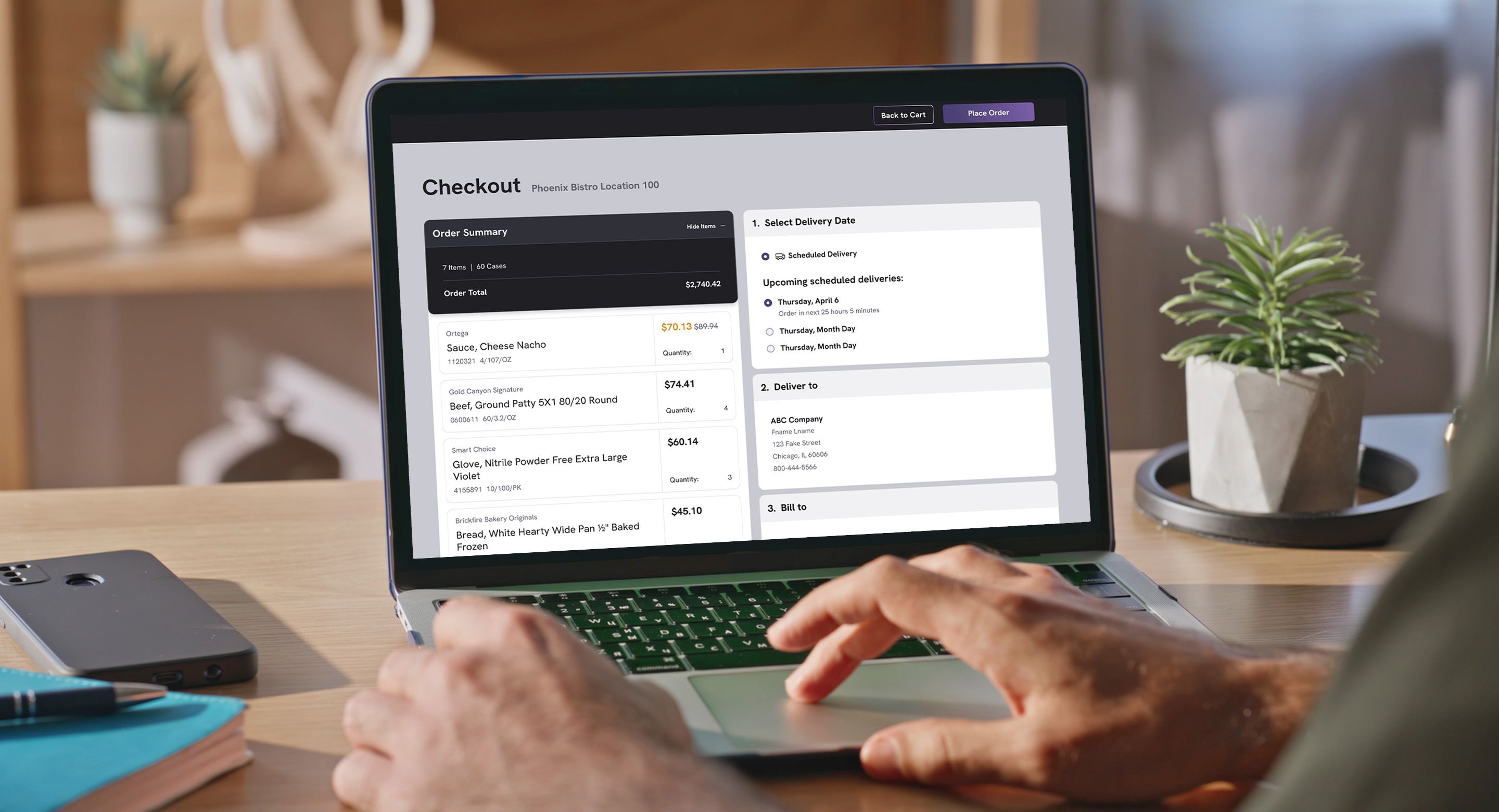 Person using laptop to complete an online wholesale food order checkout in a bright workspace.