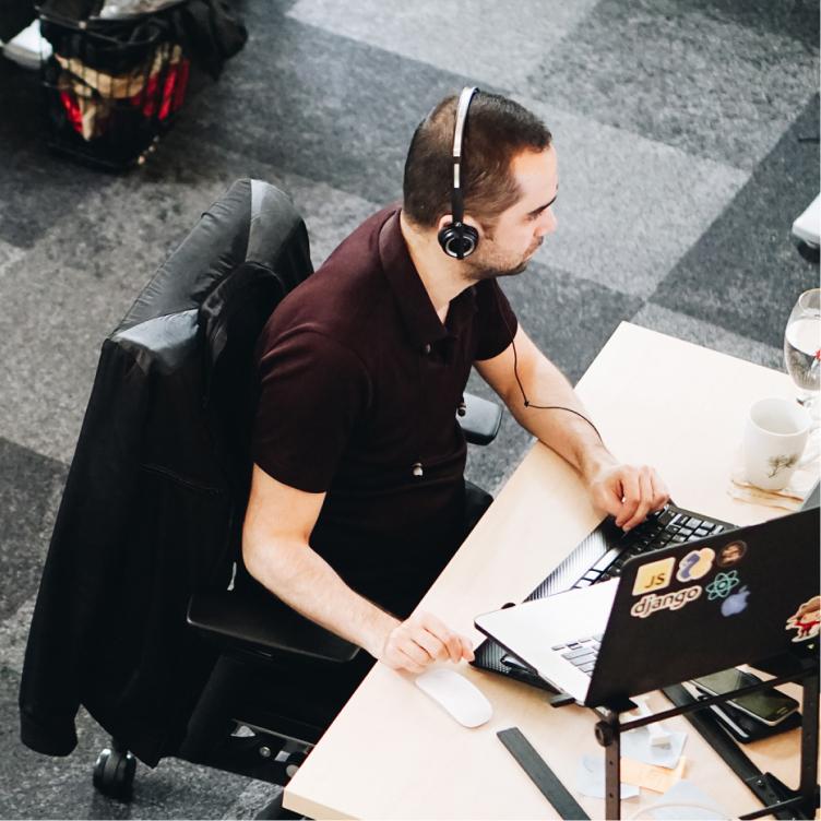 Person wearing a headset working on a laptop at an office desk.