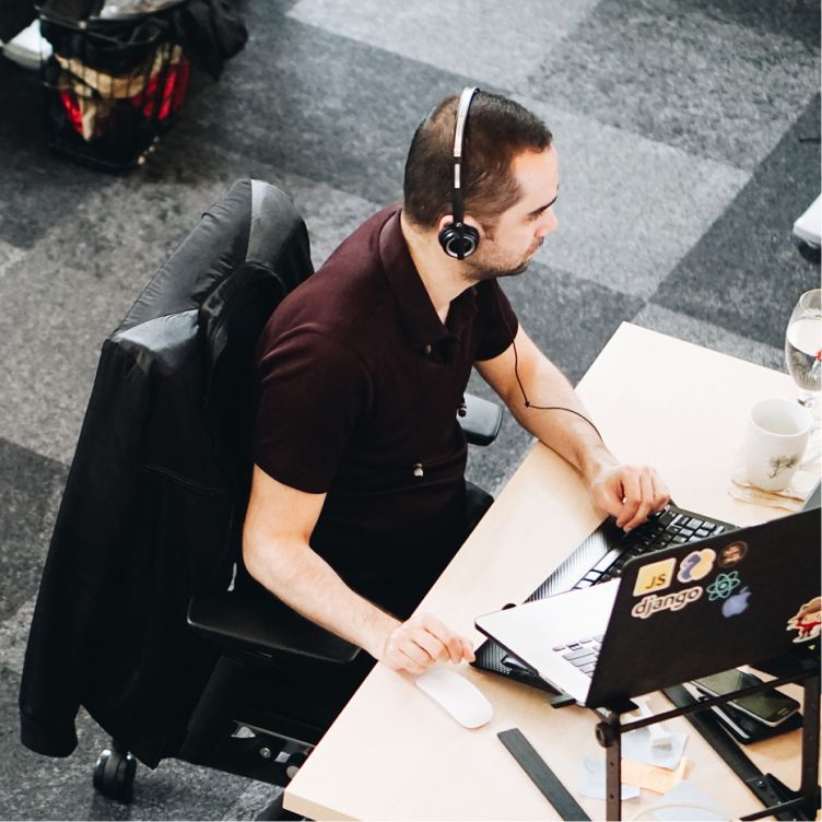 Person wearing a headset working on a laptop at an office desk.