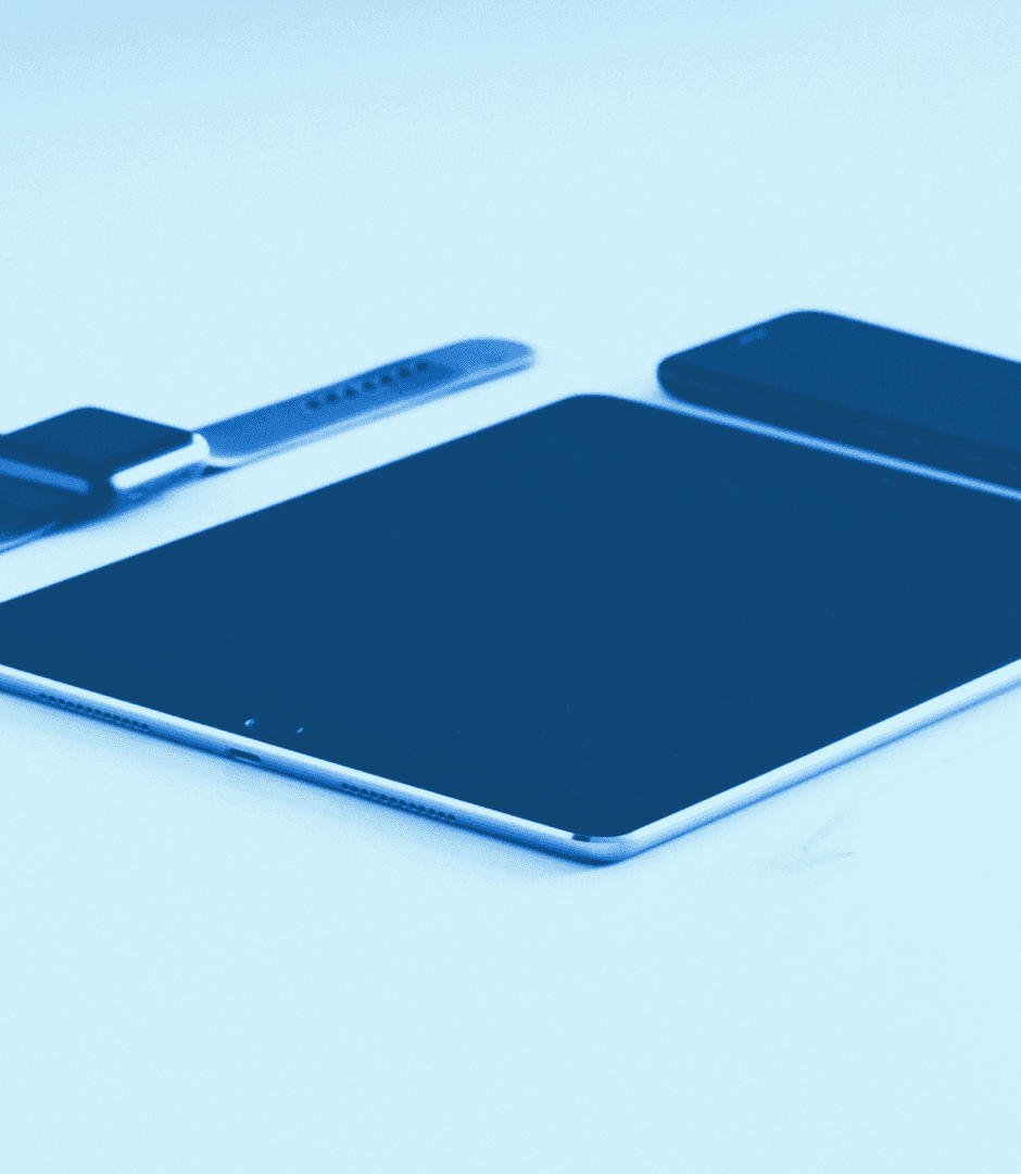 An iPad, an iPhone and a smartwatch or wearable device layed flat on a surface.