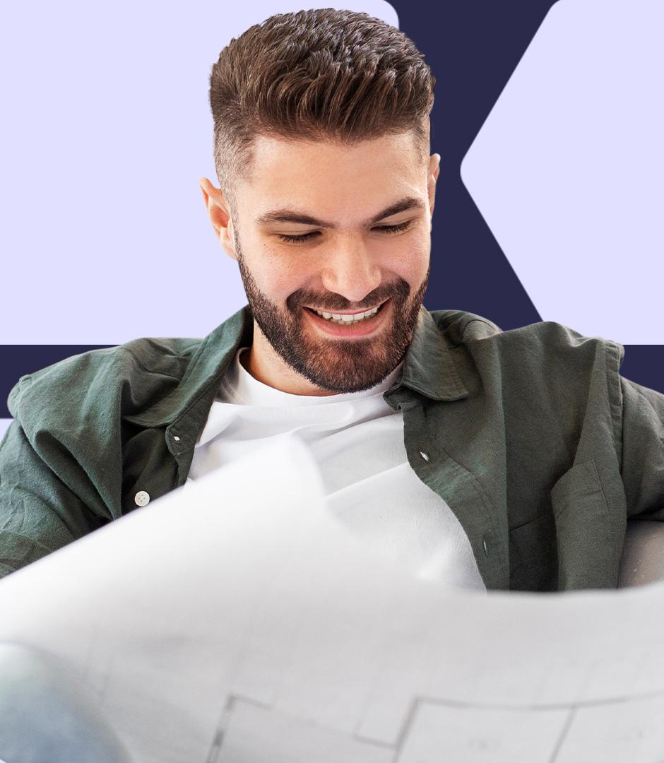 A man is holding papers and smiling while looking at the contents on them.