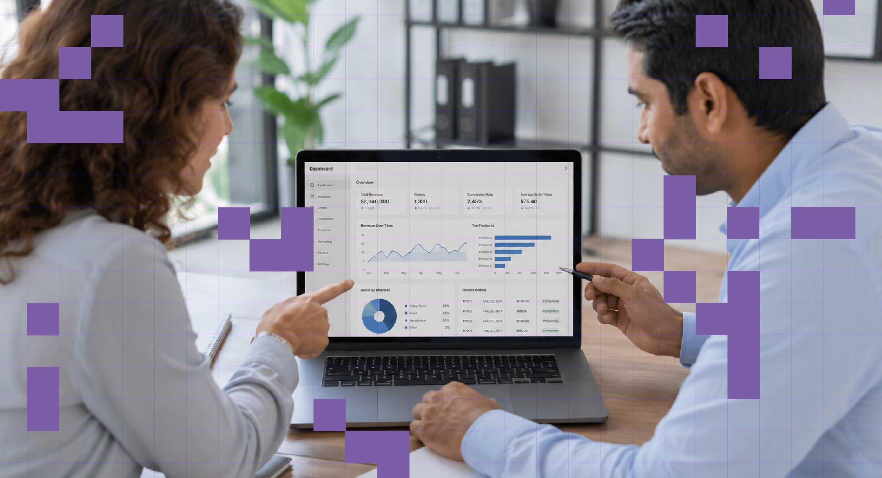 Two colleagues discuss the data presented on a digital dashboard.