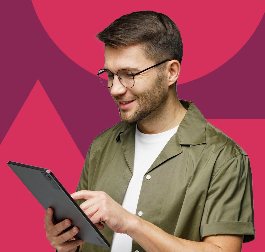 A smiling man wearing glasses and an olive shirt interacts with a tablet.