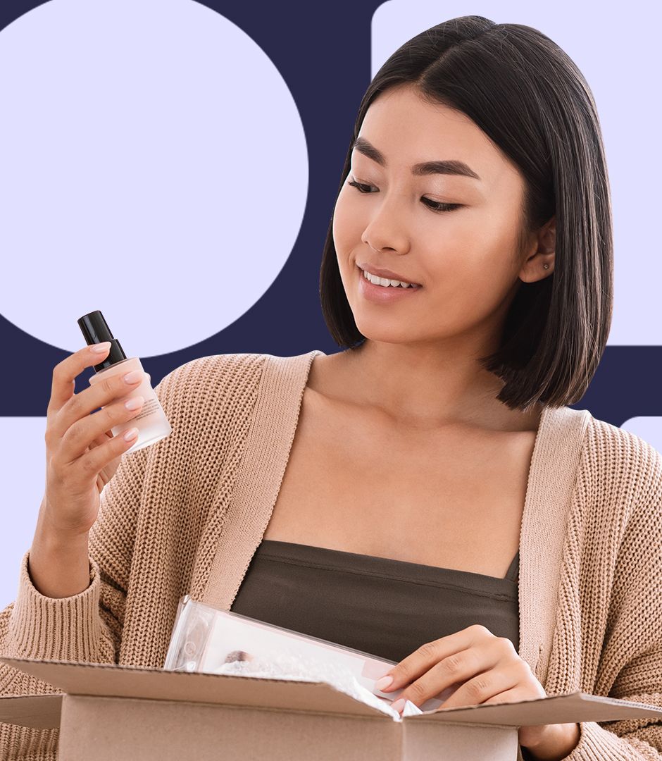 A photo of a woman holding a beauty product in one hand that she has removed from a box. Other items appear to still be in the box has she examines the first.