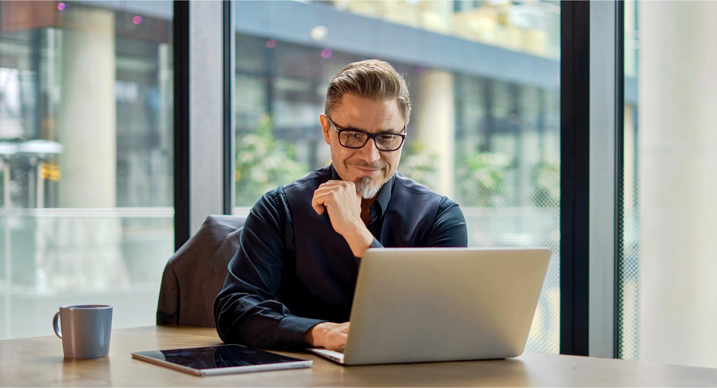A photo of a man seated at a desk in an office with a laptop in front of him