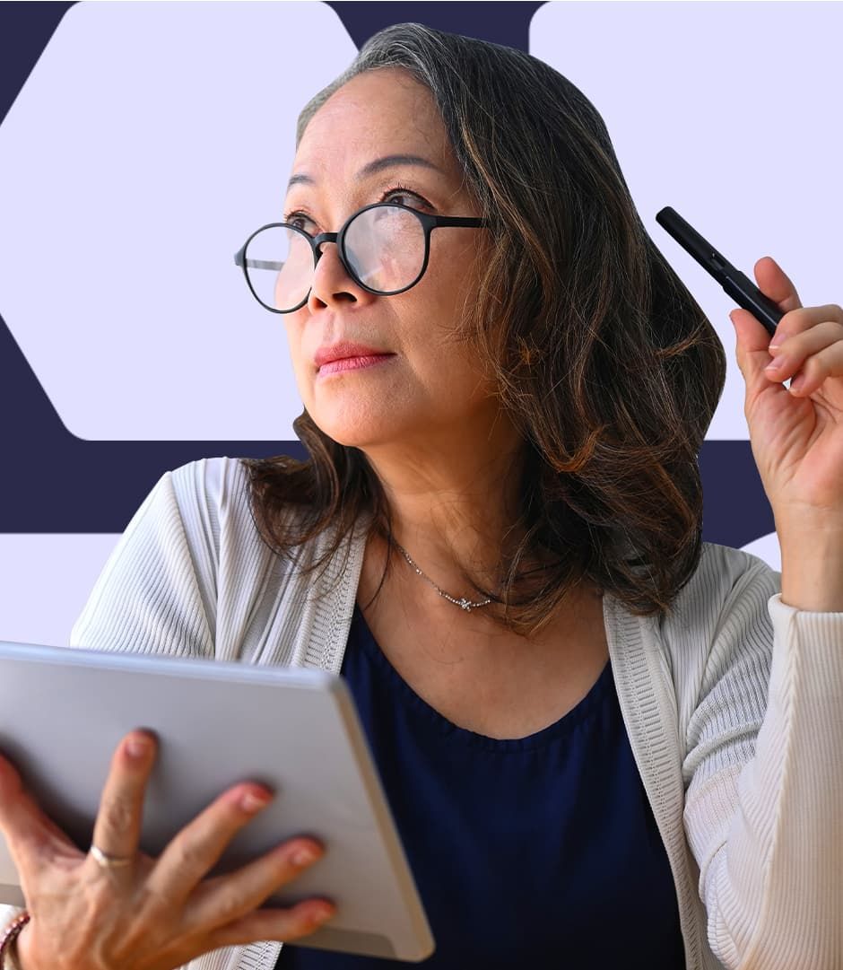 A woman holding an iPad in one hand and a pen in the other, looking off in a thoughtful gaze.