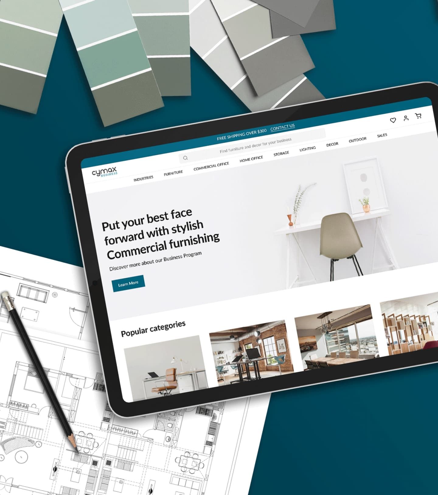 Flatlay of Cymax Group’s website on an iPad, surrounded by a floor plan rendering and green paint chips.