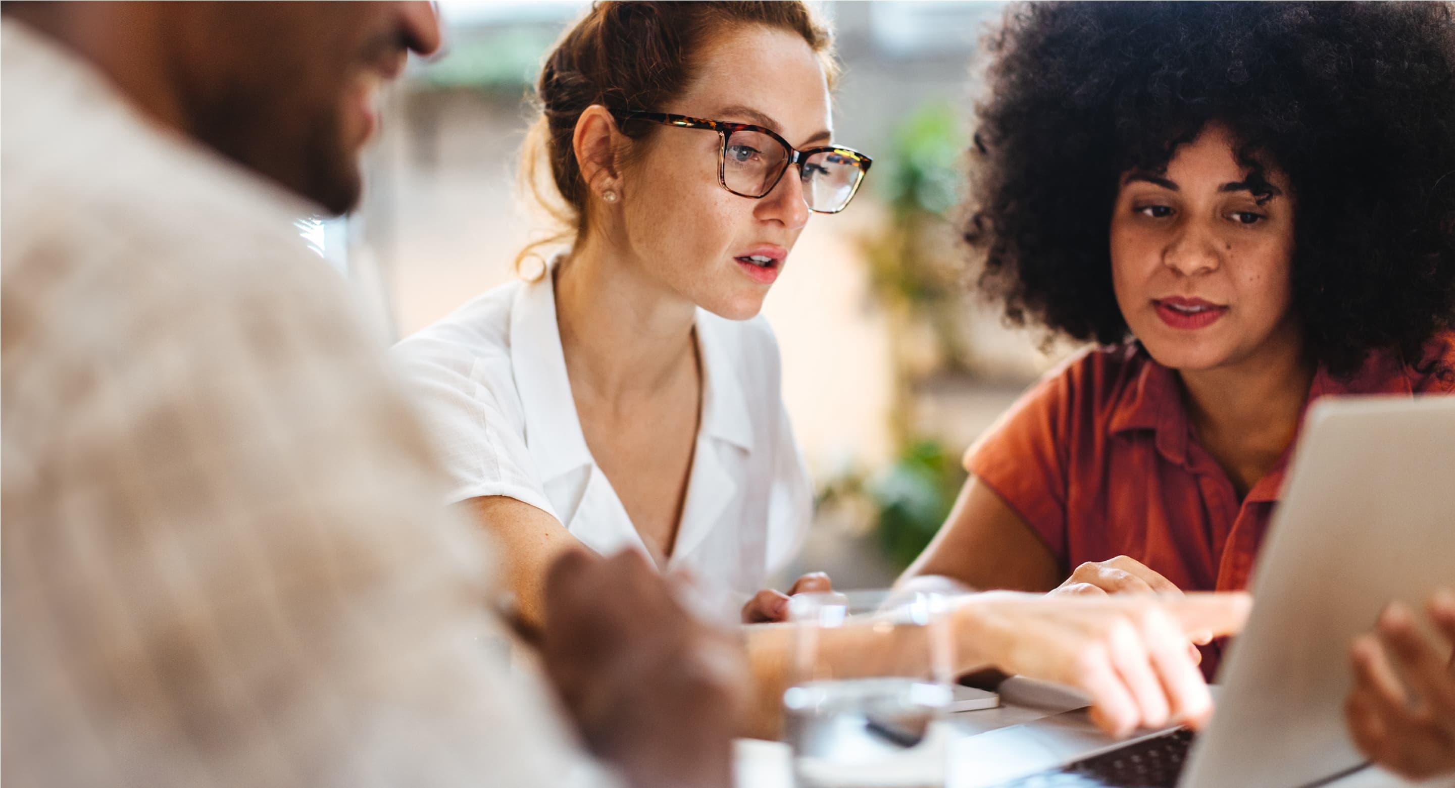Colleagues working together at a laptop discussing what they see on the screen.